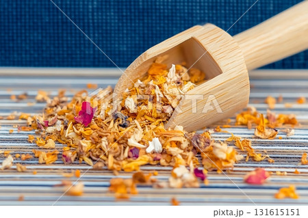 Wooden Scoop Overflowing with Colorful Dried Flowers on Striped Tablecloth Surface Wooden Scoop Overflowing with Colorful Dried Flowers on Striped Tablecloth Surface 131615151