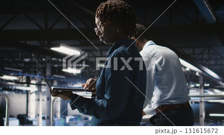Data center engineer walking on industrial platform, running diagnostics on equipment to identify errors. Server farm IT professionals preventing rigs failure to minimize downtime, Data center engineer walking on industrial platform, running diagnostics on equipment to identify errors. Server farm IT professionals preventing rigs failure to minimize downtime, 131615672
