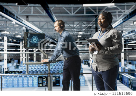 Team of data center IT professionals assisting users with AI troubleshooting, delivering technical support. Server farm colleagues chatting in headset microphone with users in need of assistance Team of data center IT professionals assisting users with AI troubleshooting, delivering technical support. Server farm colleagues chatting in headset microphone with users in need of assistance 131615696