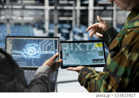 Team of army workers in data center mapping airborne activity using predictive AI tech on devices. Military units in server room flagging unusual movement using deep learning detection tools on tablet 131615927