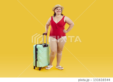 Happy young fat woman tourist in red swimsuit with suitcase on yellow color background 131616544