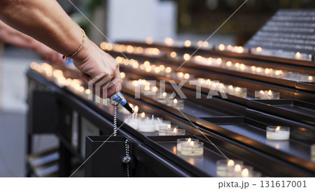 People lighting candles in a quiet space during a reflective moment in a serene setting People lighting candles in a quiet space during a reflective moment in a serene setting 131617001
