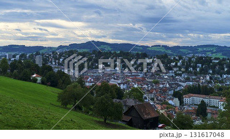 View of a Swiss town surrounded by hills and lush greenery during early evening View of a Swiss town surrounded by hills and lush greenery during early evening 131617048