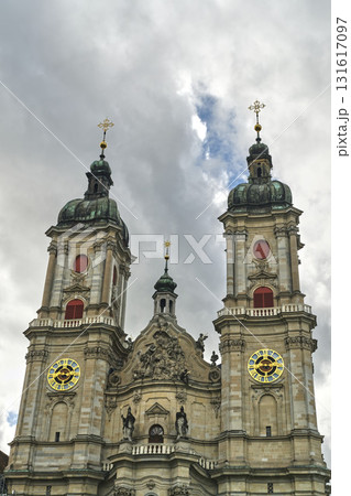 Historic church towers under cloudy sky with golden clock faces in Switzerland 131617097