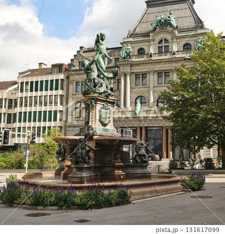 Elegant fountain and historic architecture in a bustling urban square during a sunny day Elegant fountain and historic architecture in a bustling urban square during a sunny day 131617099