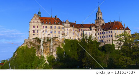 Beautiful historic castle perched on a hill surrounded by lush greenery under a clear blue sky 131617537
