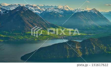 Majestic view of Swiss mountains and lake during sunset with vibrant greenery and snow-capped peaks Majestic view of Swiss mountains and lake during sunset with vibrant greenery and snow-capped peaks 131617622