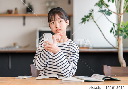 家でスマホを使いながら勉強する小学生,中学生の女の子,子供(困る,考える） 131618612