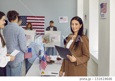 Portrait of happy young female poll worker with clipboard at American ballot station 131619686