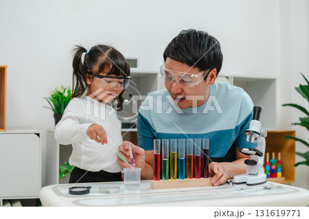 toddler girl scientist study using pipette dropping liquid with test tube and beaker. learning science with father 131619771