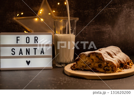 Lightbox with text FOR SANTA Traditional German Christmas stollen cake with glass of pouring milk for SANTA in background of handmade festive decor. Winter holiday treats. Vegan baking recipe Lightbox with text FOR SANTA Traditional German Christmas stollen cake with glass of pouring milk for SANTA in background of handmade festive decor. Winter holiday treats. Vegan baking recipe 131620200