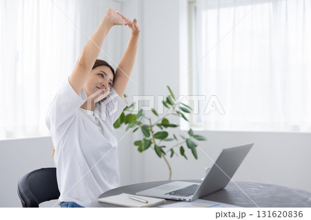 パソコン作業中に伸びをしてリフレッシュする女性 パソコン作業中に伸びをしてリフレッシュする女性 131620836