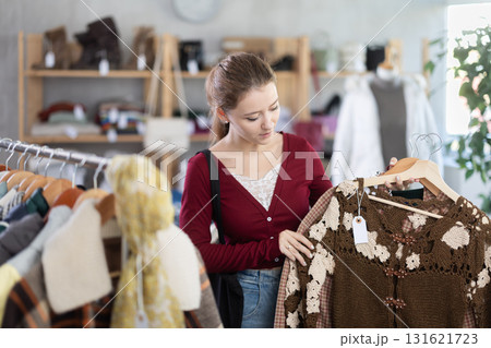 Young woman chooses cardigan in clothing store 131621723
