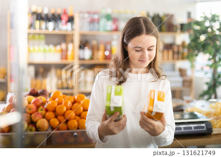 Teenage girl choosing peach and apple juices 131621749