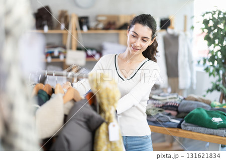 Young woman chooses outerwear in store Young woman chooses outerwear in store 131621834