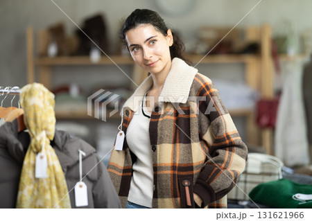 Armenian woman try on plaid jacket in store and carefully examines her reflection in mirror 131621966