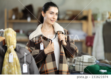 Young woman trying on plaid jacket in store Young woman trying on plaid jacket in store 131621974