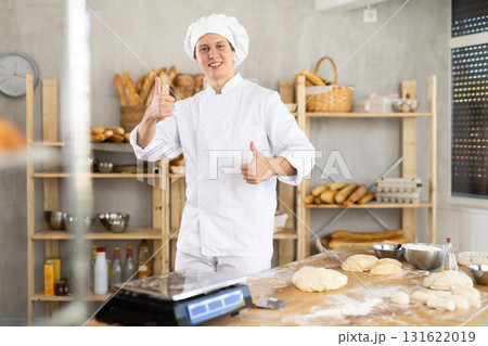 Portrait of smiling young male baker in uniform in bakery Portrait of smiling young male baker in uniform in bakery 131622019
