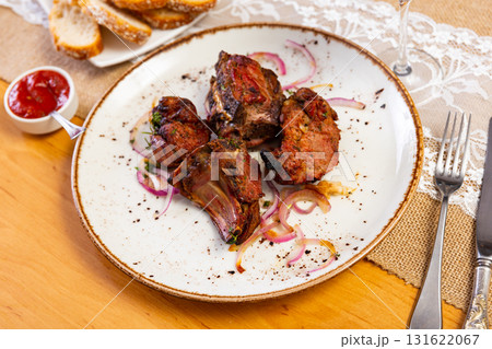 There is plate with cooked lamb barbecue shashlik on wooden table. Pieces of lamb fried on open fire There is plate with cooked lamb barbecue shashlik on wooden table. Pieces of lamb fried on open fire 131622067
