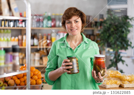 Woman chooses tomatoes and cucumbers in a marinade 131622085
