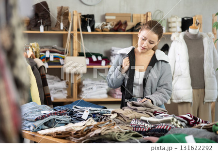 woman stands near the counter with warm pants and chooses them 131622292