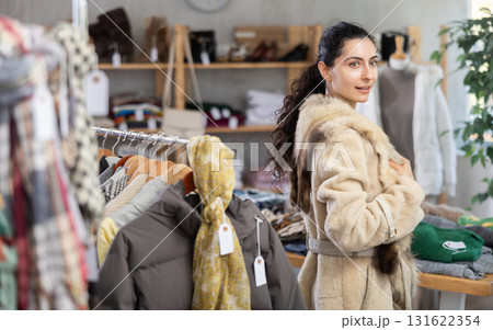 Female shopper chooses beautiful fur coat in clothing store Female shopper chooses beautiful fur coat in clothing store 131622354
