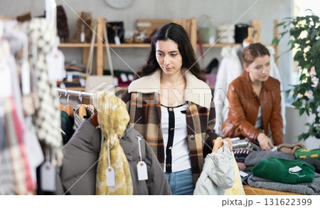 Young woman chooses down jacket in clothing store 131622399