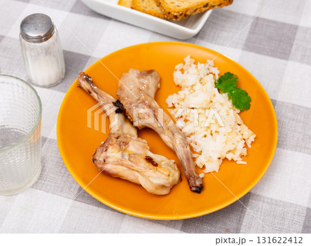 Lunch is served on plate - baked pieces of young rabbit with side dish boiled rice. 131622412