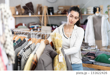 Young woman chooses outerwear in store 131622426