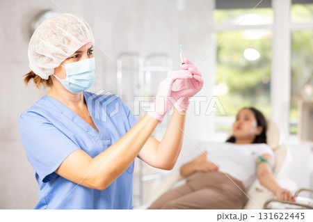Middle-aged doctor giving injection into vein Middle-aged doctor giving injection into vein 131622445