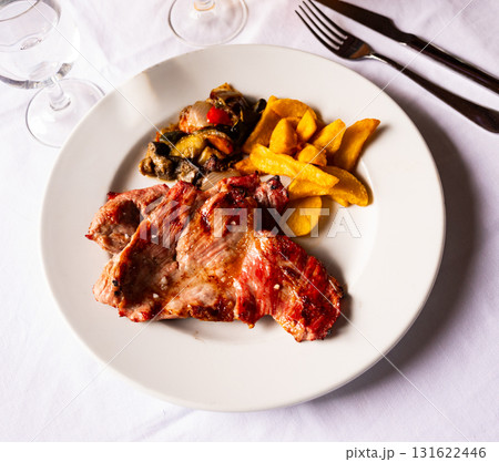 Tasty baked pork served with french fries and vegetables Tasty baked pork served with french fries and vegetables 131622446