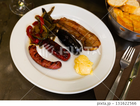 Grilled sausages and meat served with stewed vegetables and wine 131622566