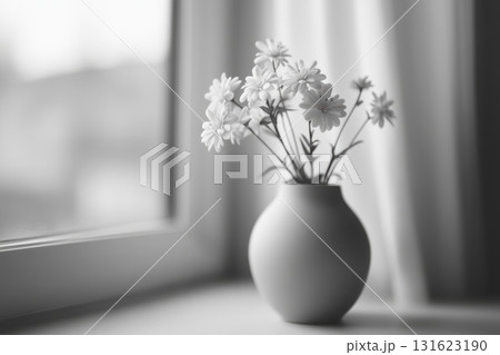 Simple white flowers in a vase on a windowsill during daylight hours 131623190