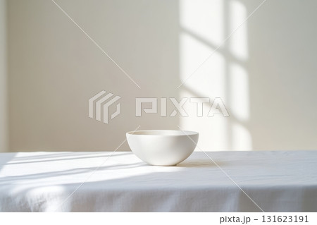 Minimalist white bowl on a table illuminated by soft sunlight 131623191