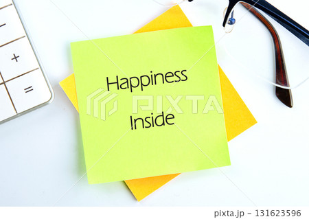 A green sticky note with Happiness Inside is resting on a yellow note near a calculator and glasses Its a reminder for positivity during the workday A green sticky note with Happiness Inside is resting on a yellow note near a calculator and glasses Its a reminder for positivity during the workday 131623596