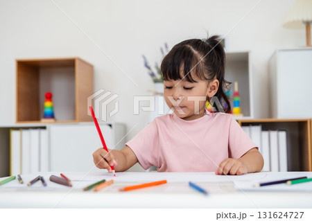 toddler baby girl training to drawing with colored pencil on desk at home 131624727