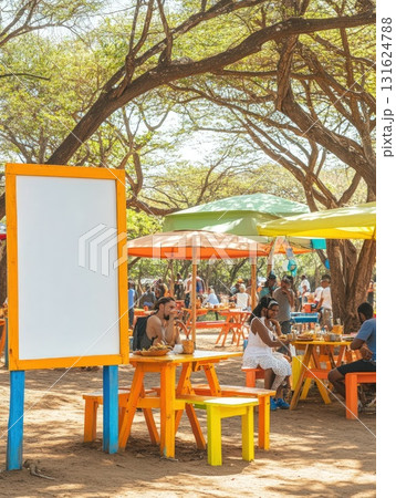 People Dining At A Colorful Outdoor Cafe Under Lush Green Trees And Bright Umbrellas In Sunshine 131624788