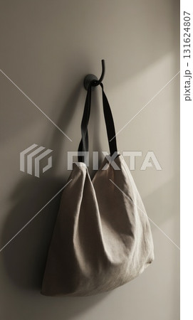 Beige Textured Bag Hanging On A Black Hook Against A Neutral Gray Wall Beige Textured Bag Hanging On A Black Hook Against A Neutral Gray Wall 131624807