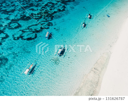 Clear ocean and white sand beach with balinese fishing boats in tropical island. Aerial view. Clear ocean and white sand beach with balinese fishing boats in tropical island. Aerial view. 131626787