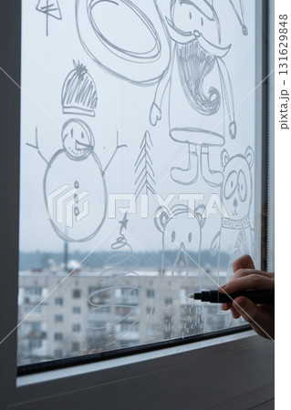 Sustainable responsible holiday decor. Female hand painting bear painted on window glass indoor at home. Christmas winter decoration. White pattern. Snow art tracery on season. Diy Sustainable responsible holiday decor. Female hand painting bear painted on window glass indoor at home. Christmas winter decoration. White pattern. Snow art tracery on season. Diy 131629848