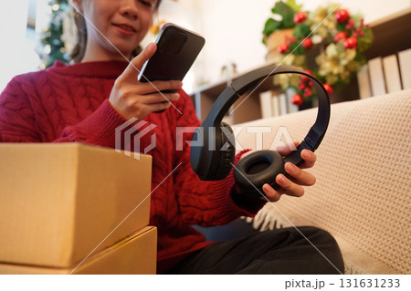 Holiday shopping. Woman checking smartphone while holding headphones. 131631233