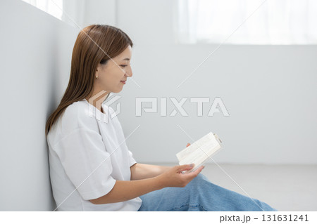 明るい室内で床に座って読書を楽しむ若い女性 明るい室内で床に座って読書を楽しむ若い女性 131631241