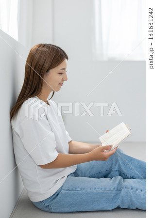 明るい室内で床に座って読書を楽しむ若い女性 明るい室内で床に座って読書を楽しむ若い女性 131631242