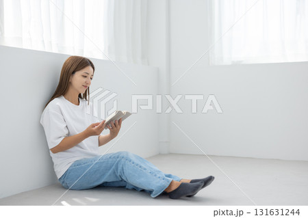 明るい室内で床に座って読書を楽しむ若い女性 明るい室内で床に座って読書を楽しむ若い女性 131631244