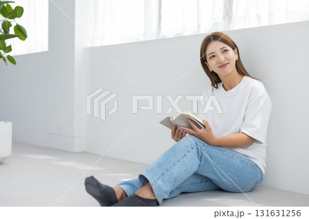 明るい室内で床に座って読書を楽しむ若い女性 131631256