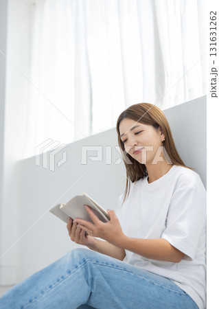 明るい室内で床に座って読書を楽しむ若い女性 明るい室内で床に座って読書を楽しむ若い女性 131631262