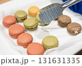 カラフルなマカロンをトングで持ち上げているところ 131631335