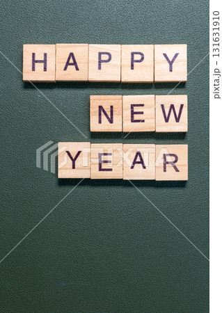 Wooden letter tiles spelling Happy New Year arranged neatly on a textured green background 131631910