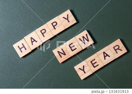 Wooden letter tiles spelling Happy New Year arranged neatly on a textured green background 131631913