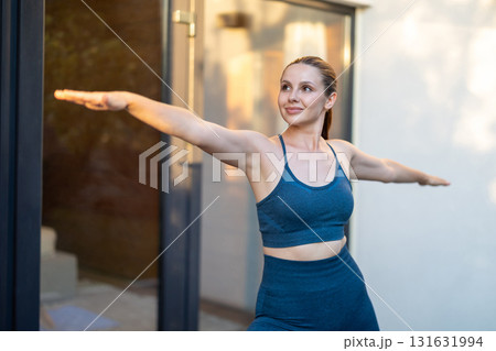 Young woman doing yoga and standing a warrior pose 131631994